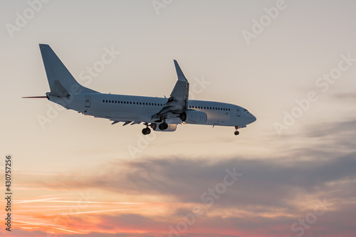 The white plane lands against the sunset.