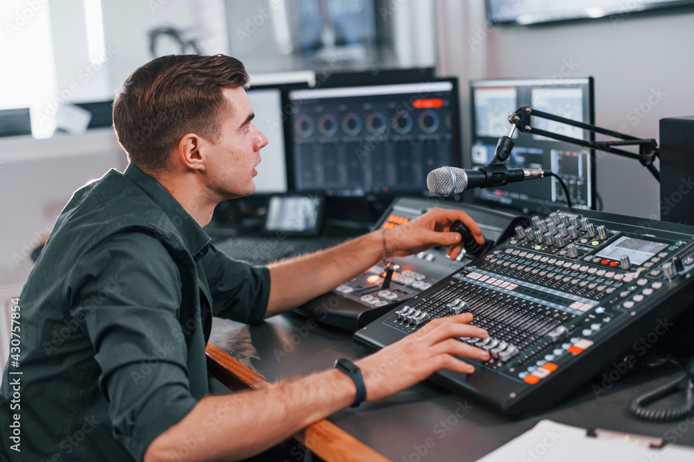 Young man is indoors in the radio studio is busy by broadcast Young man is indoors in the radio studio is busy by broadcast