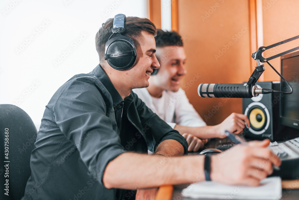 Two guys is indoors in the radio studio is busy by broadcast Two guys is indoors in the radio studio is busy by broadcast