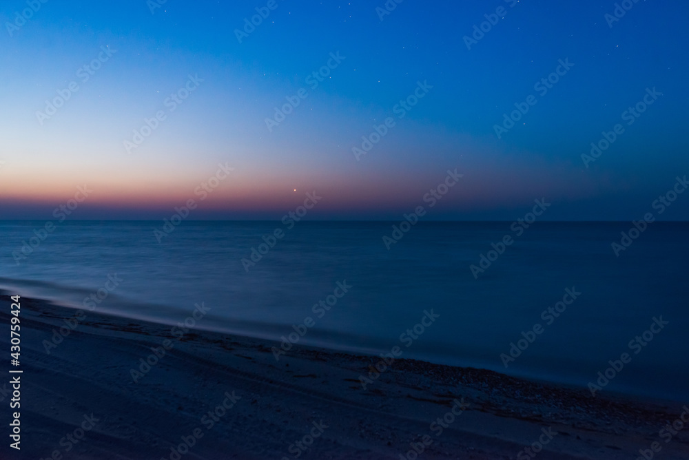 Venus in morning sky over sea coast, calm, soft waves