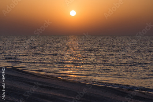 Sunrise over calm sea with clear horizon and soft waves water surface