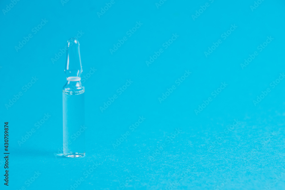 Ampoule with medicine on a blue background close-up macro, copy space. Treatment concept for coronavirus patients Ampoule with medicine on a blue background close-up macro, copy space. Treatment concept for coronavirus patients
