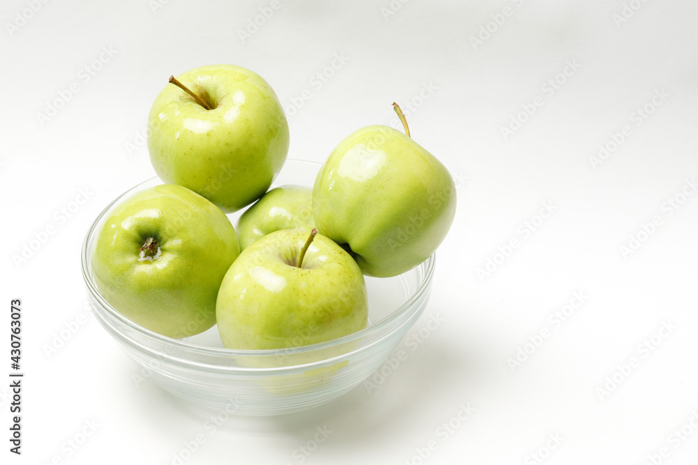 green apples in a transparent bowl on a white background green apples in a transparent bowl on a white background
