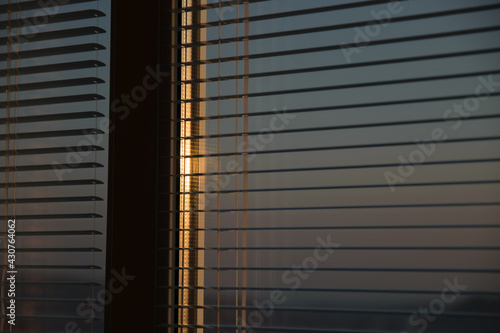 The sun shines through the blinds. Selective focus.