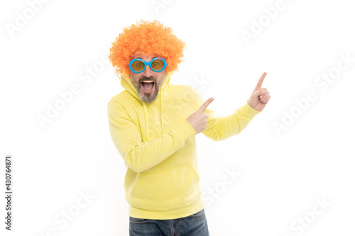 Crazy man in wig keep mouth open with surprise pointing index fingers for copy space, advertising
