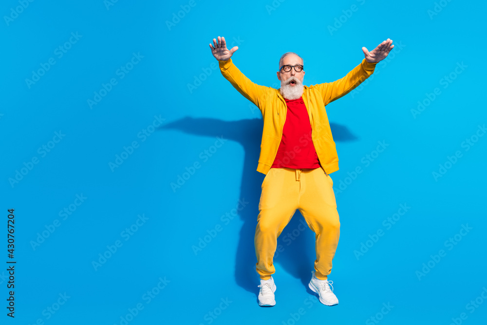 Full size photo of shocked amazed surprised grandfather dancing wear yellow tracksuit isolated on blue color background Full size photo of shocked amazed surprised grandfather dancing wear yellow tracksuit isolated on blue color background