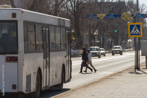 Uralsk, Kazakhstan (Qazaqstan), 18.03.2020: People cross the road in front of the bus on a pedestrian crossing. Girls crossing the road at a pedestrian crossing