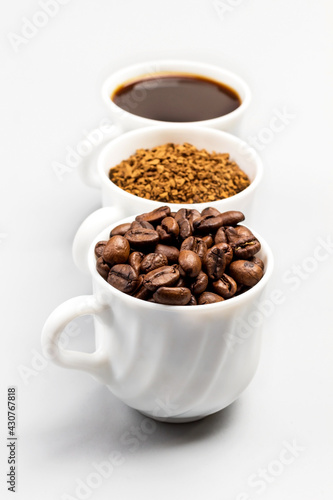 Three white cups with coffee beans  ground coffee and coffee drink