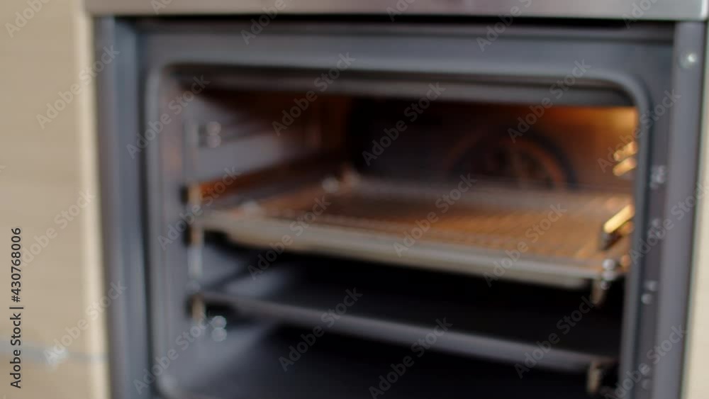 Male chef putting the dough on a baking sheet in an electric oven in the kitchen Male chef putting the dough on a baking sheet in an electric oven in the kitchen