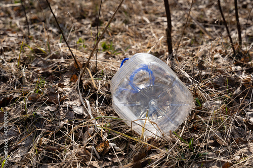 a large transparent five-liter plastic bottle tossed in the dry spring grass