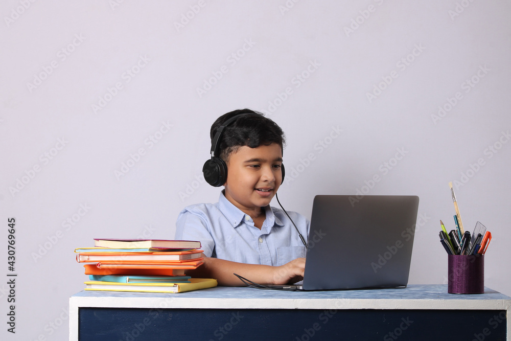 Indian male student or kid studying online using laptop. Asian child attending online school using computer. Indian male student or kid studying online using laptop. Asian child attending online school using computer.