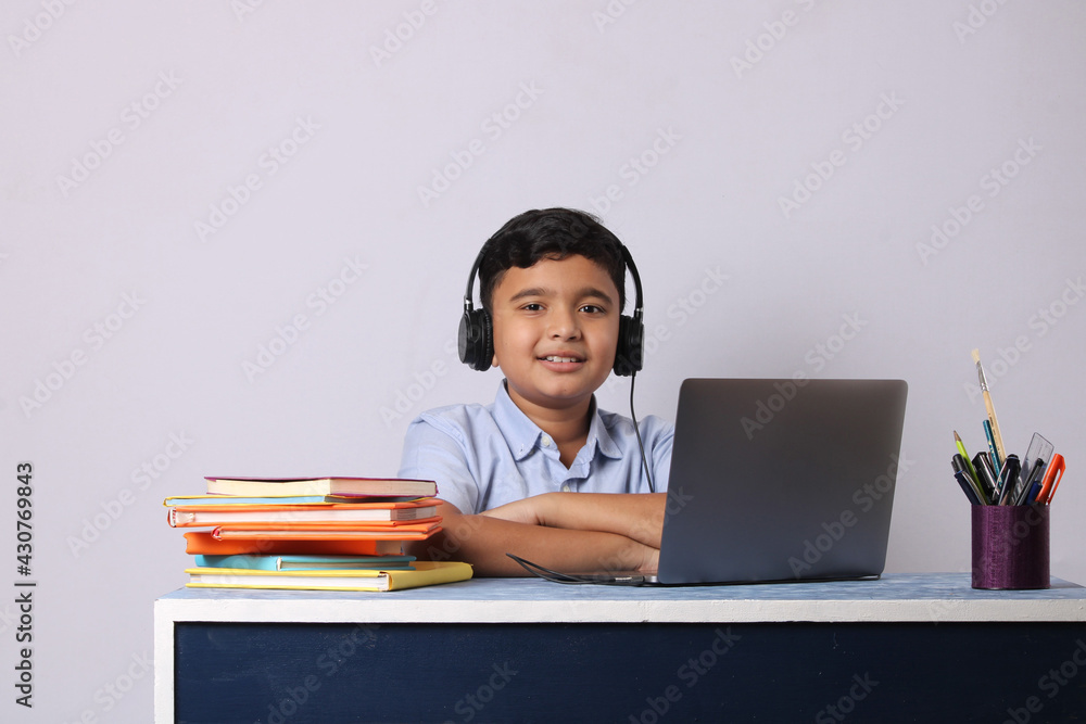 Indian male student or kid studying online using laptop. Asian child attending online school using computer. Indian male student or kid studying online using laptop. Asian child attending online school using computer.