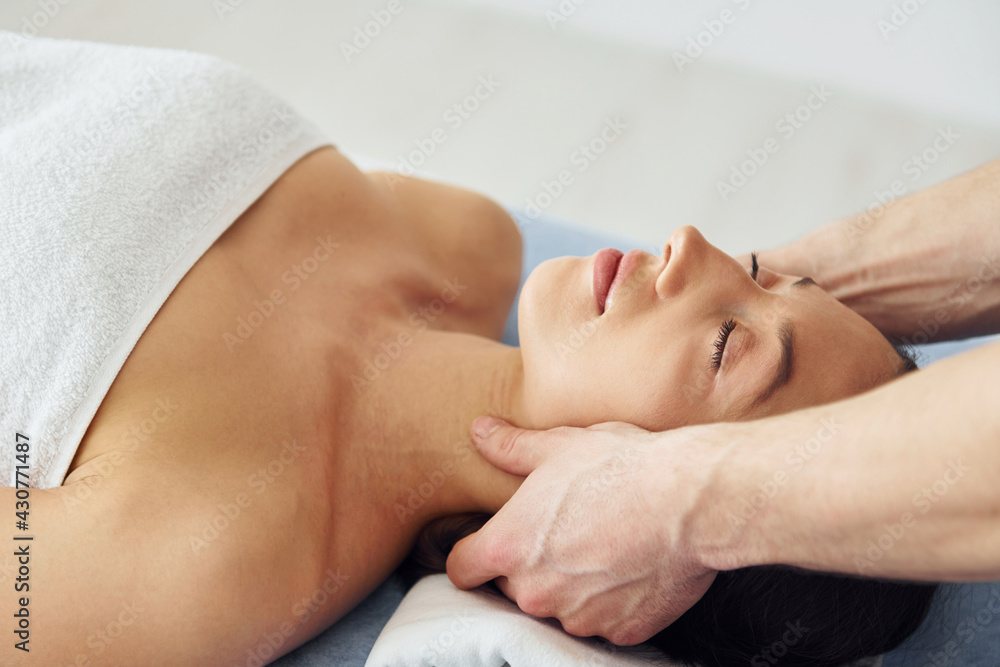 Head massage. Young woman is lying down when man doing procedure to her in spa Head massage. Young woman is lying down when man doing procedure to her in spa