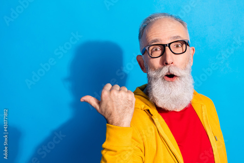 Photo of shocked amazed surprised mature man point thumb copyspace promotion isolated on blue color background