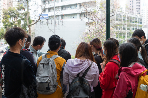 university or college students with face mask gather together to listen to professor or teacher about field hydraulic test in a borehole during field trip in Hong Kong