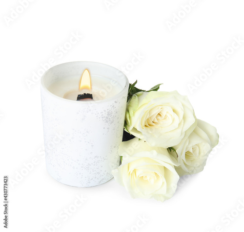 Aromatic candle with wooden wick and beautiful flowers on white background
