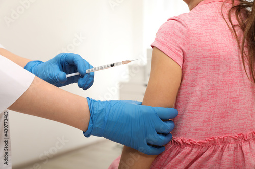 Doctor giving injection to little girl in hospital  closeup. Immunization concept