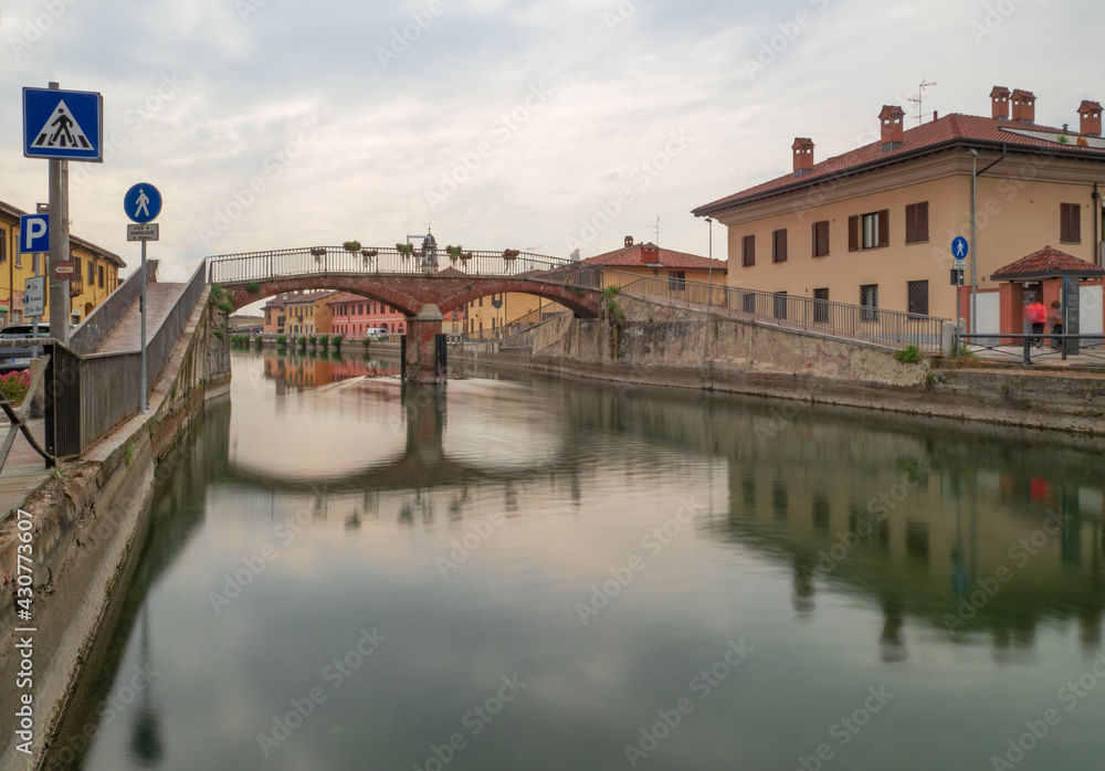 Fototapeta premium Bridge and colorful farmhouses on the ancient canal called Naviglio Grande in the countryside near Milan.Lombardy,Italy.