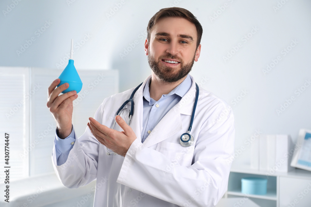 Doctor holding rubber enema in examination room Doctor holding rubber enema in examination room