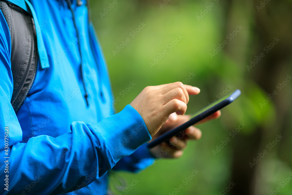 Woman hiker using smartphone in spring forest Woman hiker using smartphone in spring forest