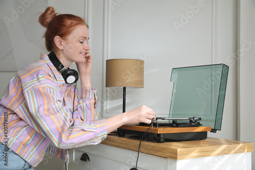 Beautiful young woman using turntable at home