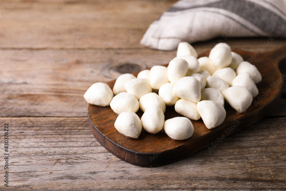 Board with delicious mozzarella cheese balls on wooden table. Space for text Board with delicious mozzarella cheese balls on wooden table. Space for text