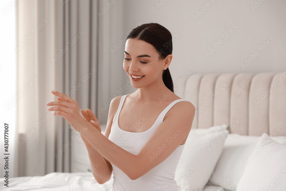 Young woman applying body cream onto her arm at home Young woman applying body cream onto her arm at home