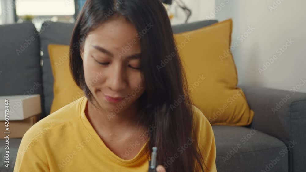 Happy asian young woman unpacking box and reading the instructions to assemble new furniture decorate house build table with carton box in living room at home.