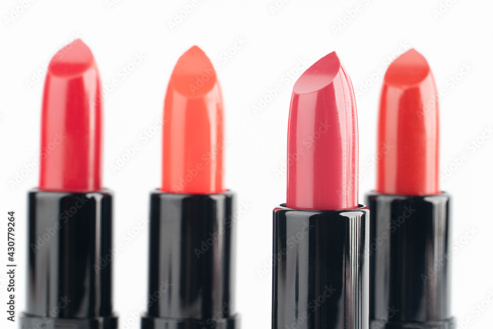 Obraz premium Red lipsticks of different shades in black tube package over white background. Makeup and cosmetics concept. Close up.