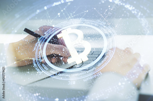 Double exposure of creative Bitcoin symbol hologram with hand writing in notepad on background with laptop. Mining and blockchain concept © Pixels Hunter