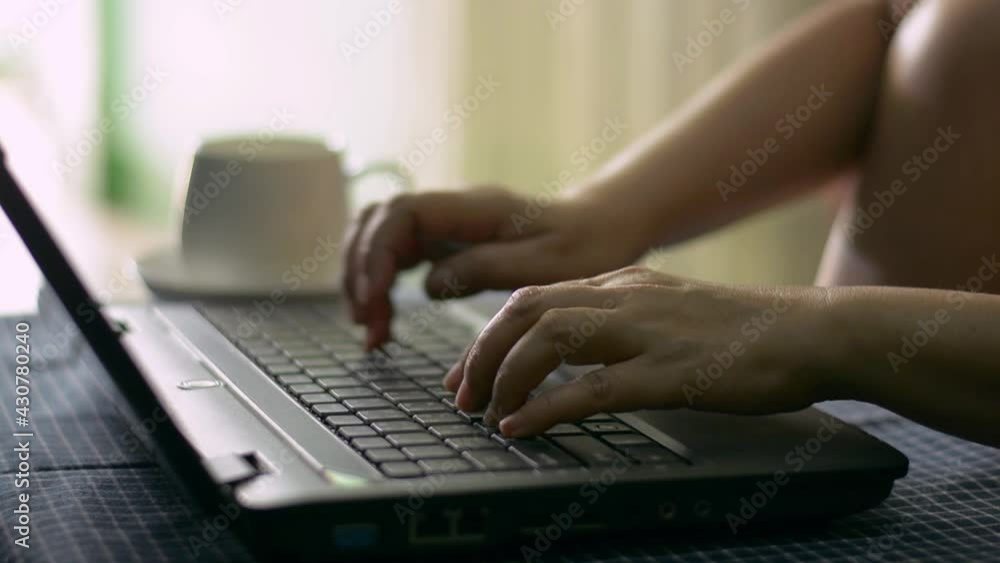 Hands of woman typing on computer keyboard and drinking coffee during work from home. Relax freelancing working on laptop at home writes post comments in social online networks. Hands of woman typing on computer keyboard and drinking coffee during work from home. Relax freelancing working on laptop at home writes post comments in social online networks.