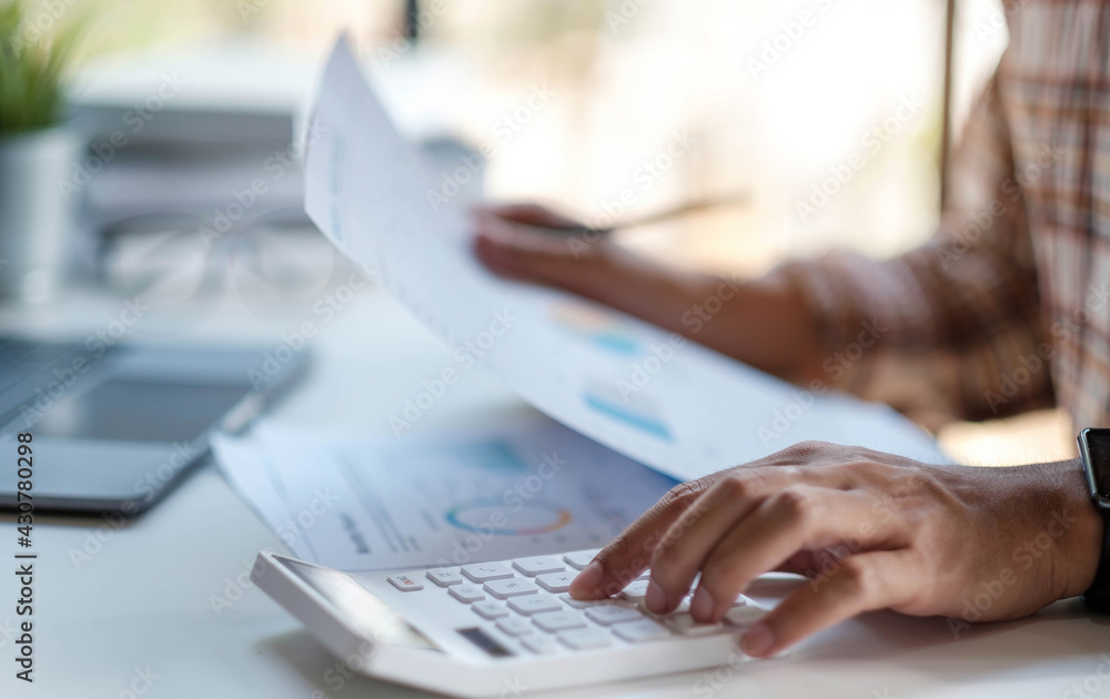Businessman or accountant hand holding pen working on calculator to calculate business data, accountancy document with laptop computer on desks. Businessman or accountant hand holding pen working on calculator to calculate business data, accountancy document with laptop computer on desks.