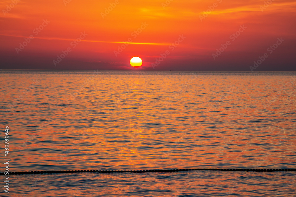Beautiful landscape - beach on sunset – red and orange sky and sunlight reflecting on sea water.