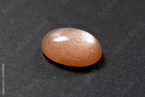 Obraz na płótnie Loose natural oval cabochon sunstone gemstone light peach color with inclusions of hematite and copper in the mineral what gives a  golden shimmer