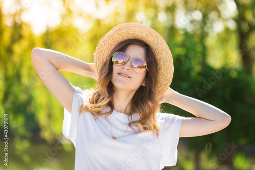 Smiling young woman in a white t-shirt, straw hat and sunglasses. Summer vacation