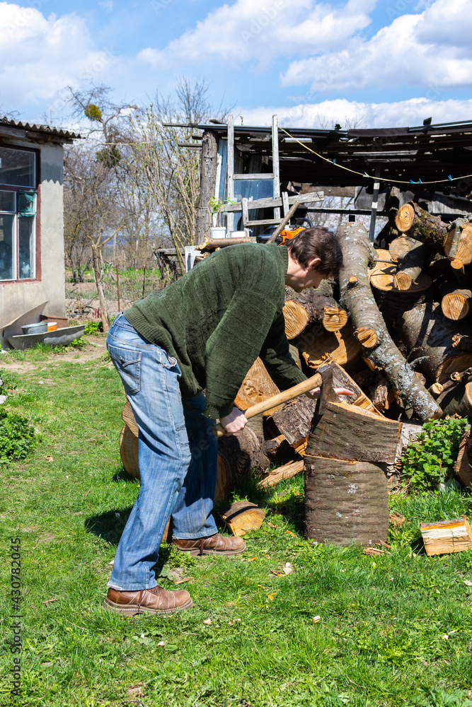 Man with an ax chopping a log in the back yard, firewood for the winter Man with an ax chopping a log in the back yard, firewood for the winter