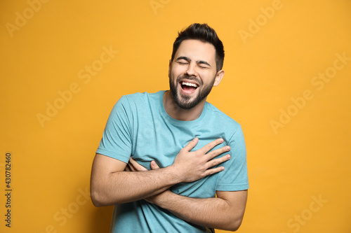 Young man laughing on yellow background. Funny joke