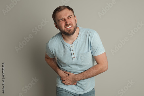 Man suffering from acute appendicitis on light grey background photo