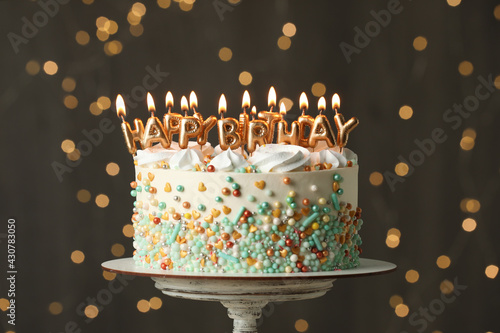 Photography Beautiful birthday cake with burning candles on stand against festive lights