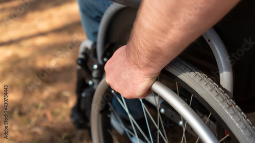 Close up, hand of young man steering the wheel of the wheelchair. Selective focus
