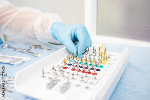 set of instruments for dental implantation on the table at the dentist. Doctor in blue gloves chooses an instrument photo