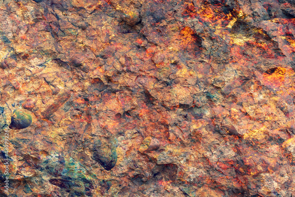 Background texture of natural wall made of brown, red, and yellow stones. Horizontal image.