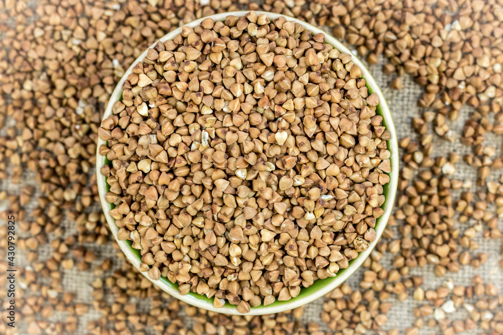 buckwheat (raw, dry) is poured into a round plate, defocused buckwheat is scattered around buckwheat (raw, dry) is poured into a round plate, defocused buckwheat is scattered around