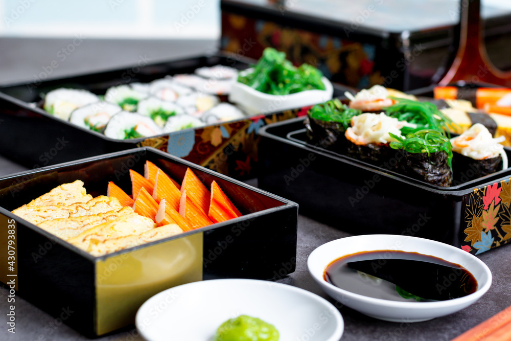 Set of variety sushi, Tamagoyaki, crabsticks sushi and maki in bento box served with soy sauce and wasabi. Delicious japanese food. Set of variety sushi, Tamagoyaki, crabsticks sushi and maki in bento box served with soy sauce and wasabi. Delicious japanese food.