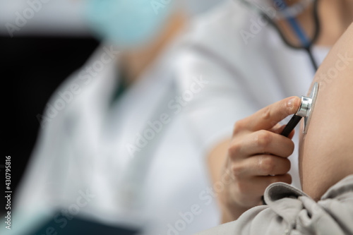 Close-up view of a lady doctor auscultating a pregnant woman's abdomen with a stethoscope. Professional doctor's office