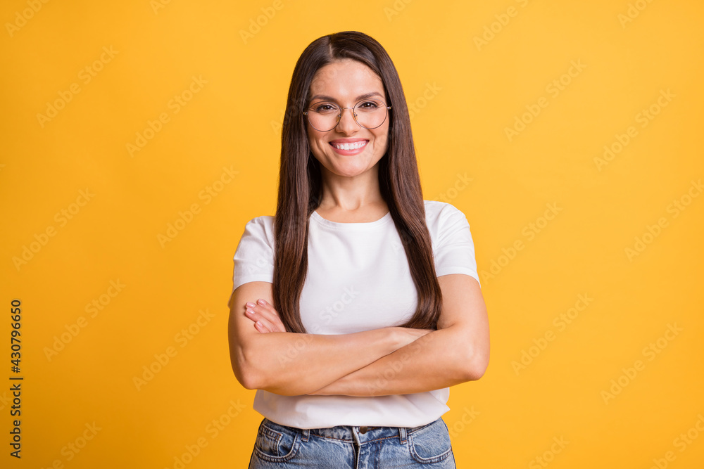 Photo of confident happy woman wear glasses crossed hands beaming smile isolated on yellow color background Photo of confident happy woman wear glasses crossed hands beaming smile isolated on yellow color background