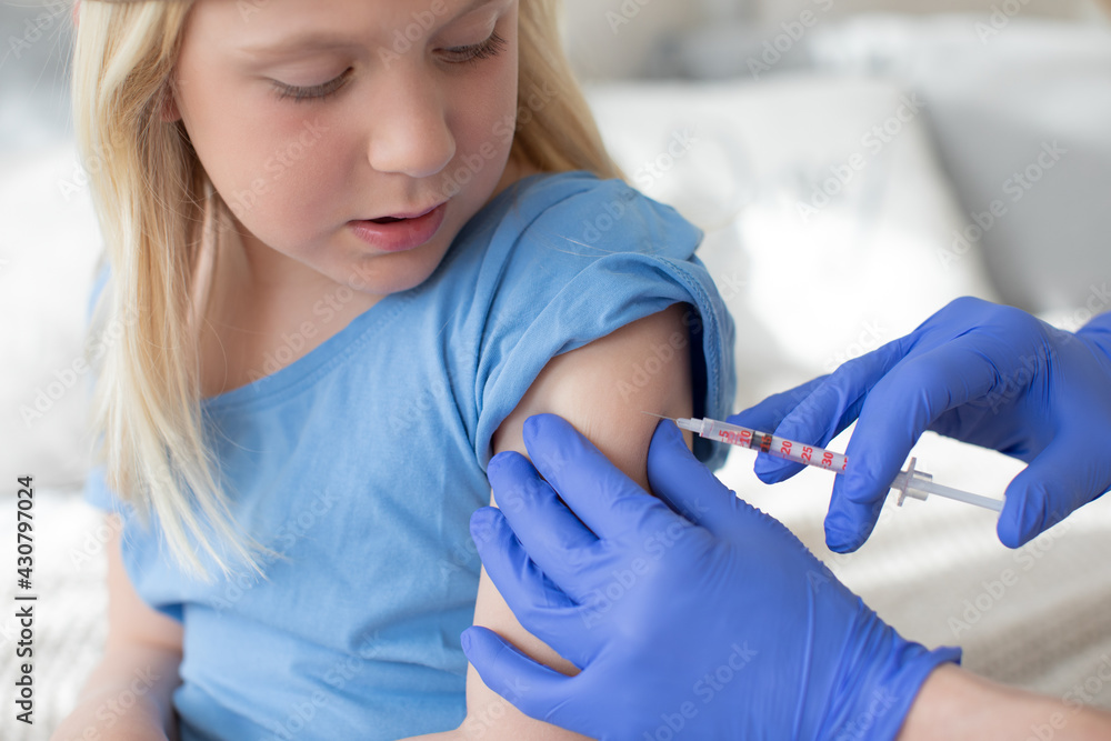Blonde child, girl,boy, looking at the syringe at the doctor. While being vaccinated or receiving a shot. Blonde child, girl,boy, looking at the syringe at the doctor. While being vaccinated or receiving a shot.