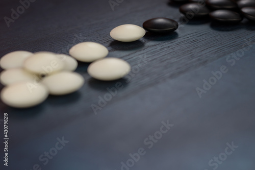 Black and white stones of traditional Chinese game go on blue table