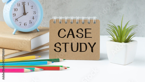 Case study memo written on a notebook with pencils, alarm clock.