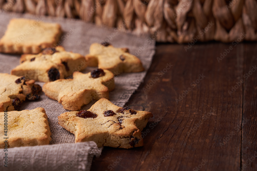 Fototapeta premium Healthy homemade gluten-free, lactose-free cookies of various shapes without sugar with raisins and chocolate on a dark brown wooden background